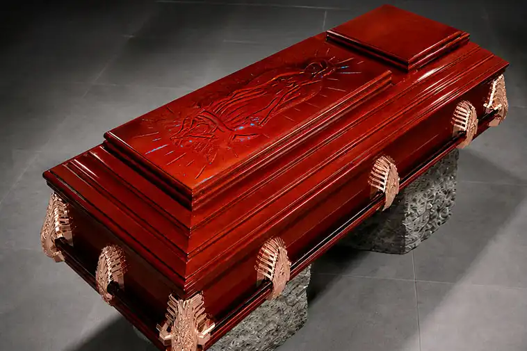 Ataúd de madera de lujo con asas de metal; lleva grabado en la cubierta una figura religiosa. Es usado para homenajes de despedida en la Funeraria Valparaíso, ubicada en Toluca, Estado de México.