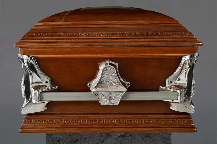 Detalle frontal de ataúd Premium con diseño curvo, madera pulida y asas metálicas decorativas para servicios funerarios.