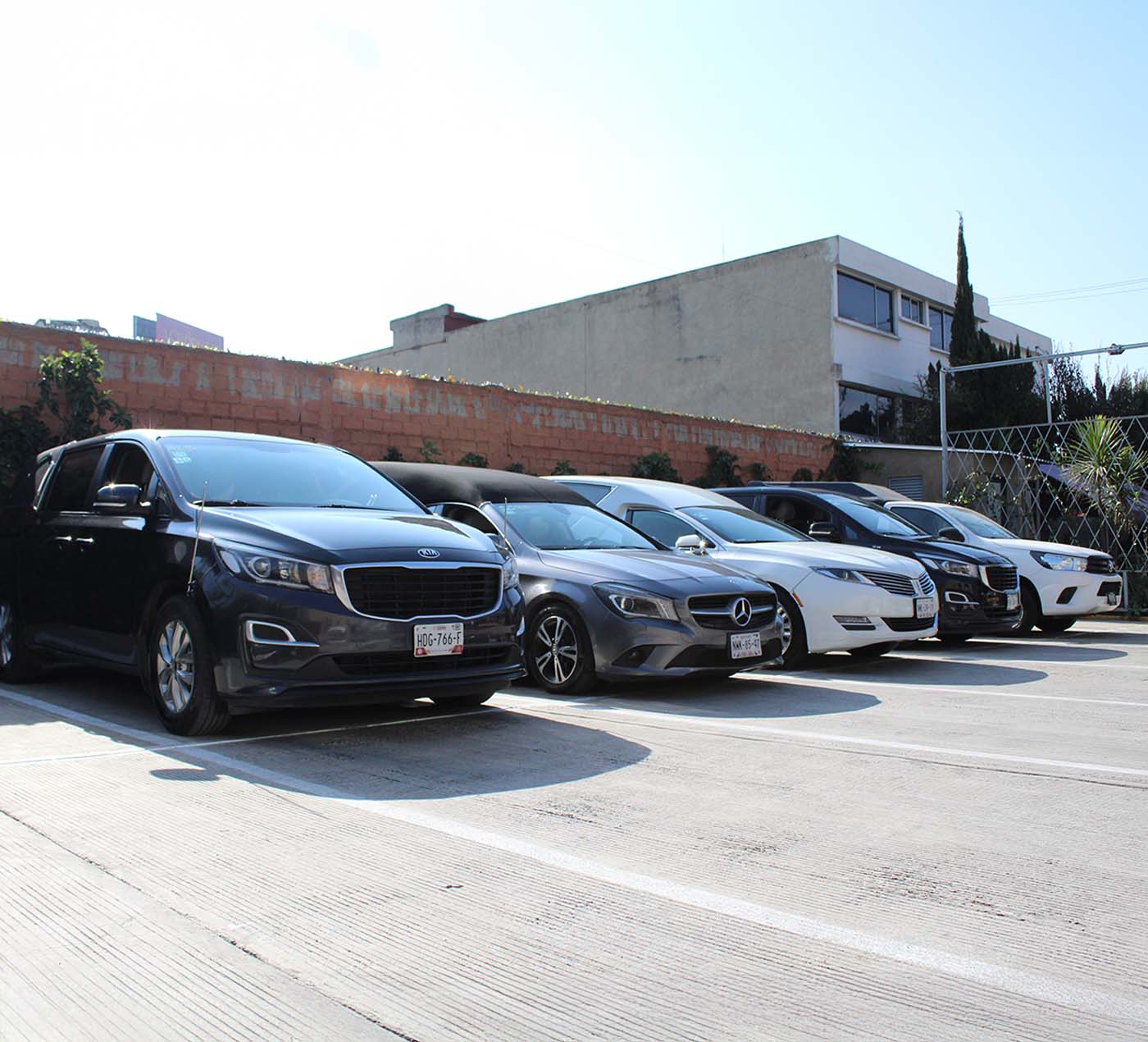 Cinco carrozas fúnebres de distintos modelos, tres son de color negro y una color blanco.