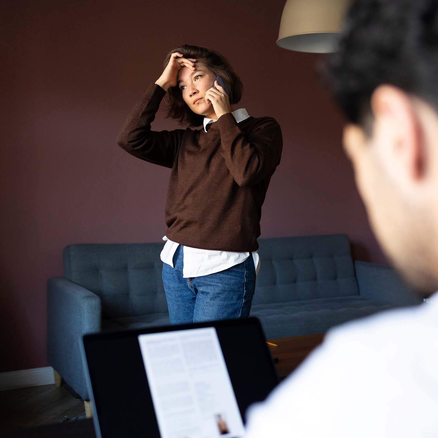 Mujer recibiendo una mala noticia por teléfono, se encuentra en el interior de su casa viste de forma casual.