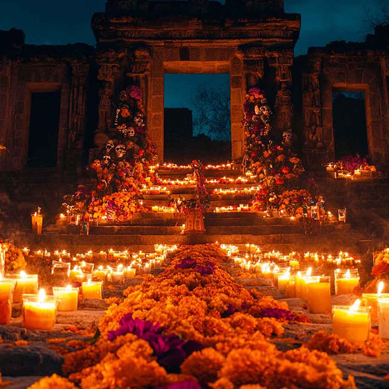Área de un panteón en México adornada con motivos del Día de Muertos, con flores y velas.