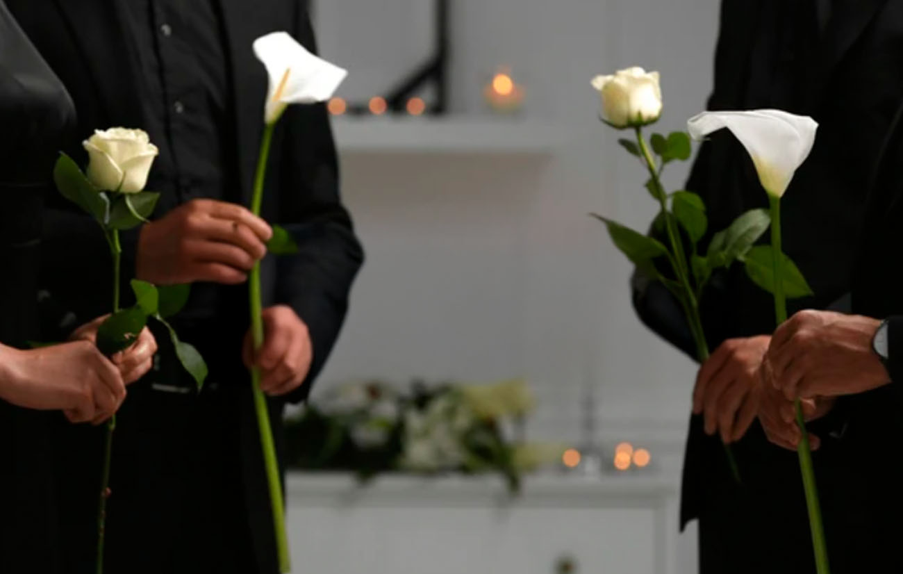 Grupo de personas en un funeral mostrando respeto y compartiendo flores para la familia.