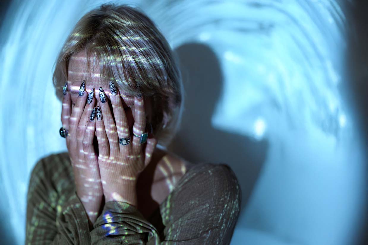 Mujer tapándose la cara expresando un profundo sentimiento de miedo.
