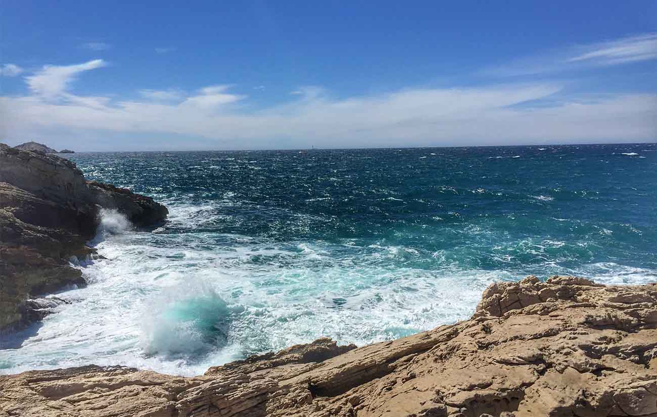 Mar extenso con un azul intenso con olas y rocas.